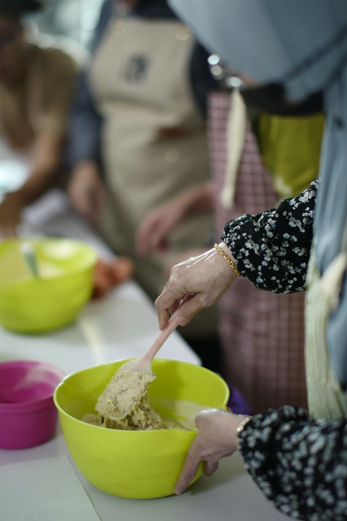 services-img Women mixing dough during a baking class in Malaysia, hands-on learning.