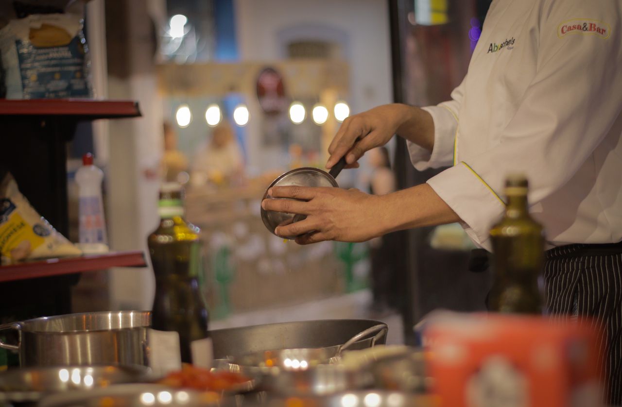 about-img A chef carefully preparing a meal in a warmly lit, cozy restaurant kitchen setting.