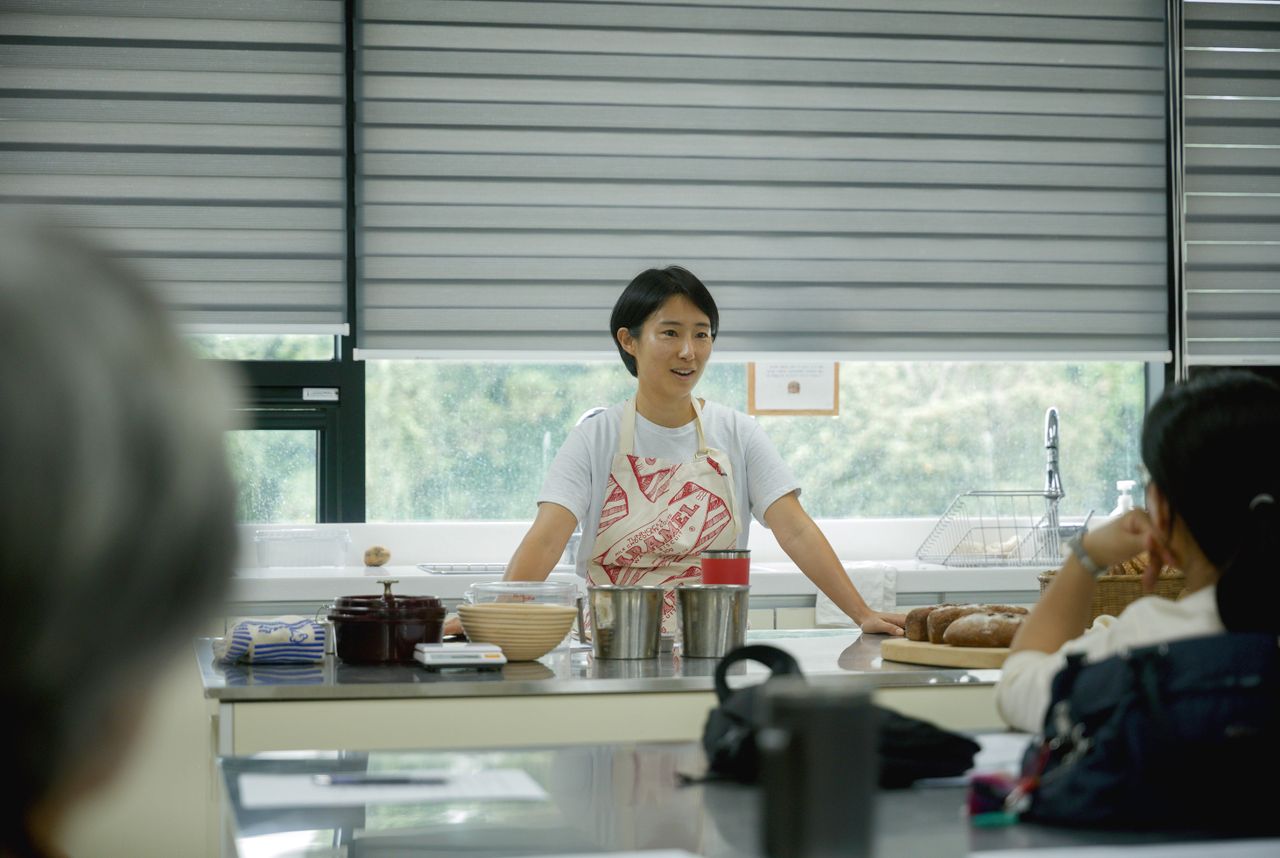 trusted-partner Chef leading a cooking class, explaining techniques to students in a bright, modern kitchen.