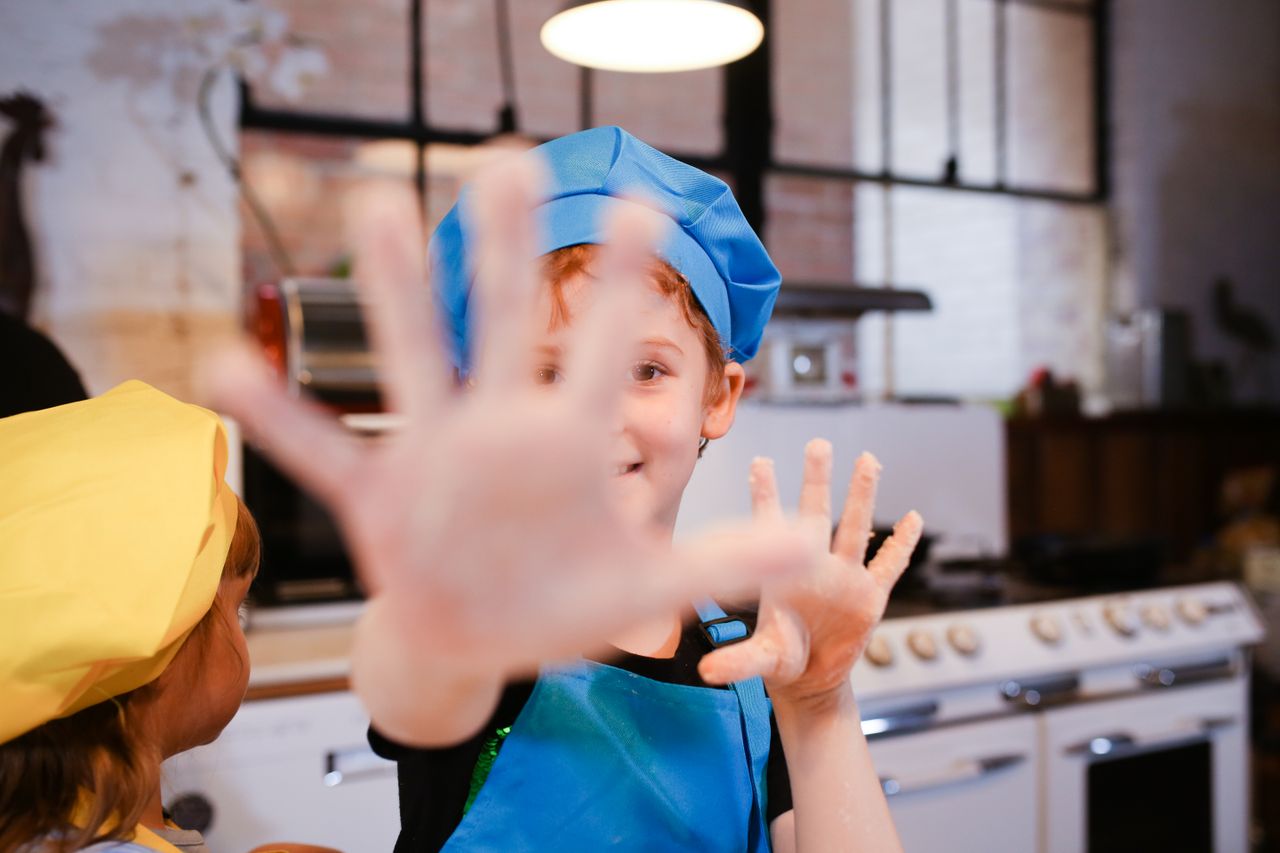 Children enjoying a hands-on cooking class, wearing chef hats and aprons in a cozy kitchen setting.
